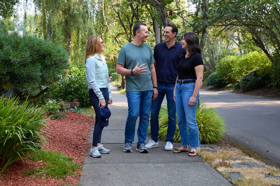 Neil and Claire Tunmore talking and laughing with their two adult children on a tree-lined Lake Oswego street